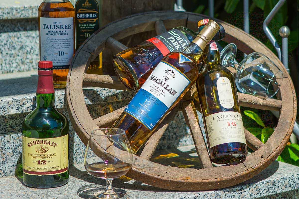 Arrangement aus besonderen Whiskysorten und urigem Wagenrad